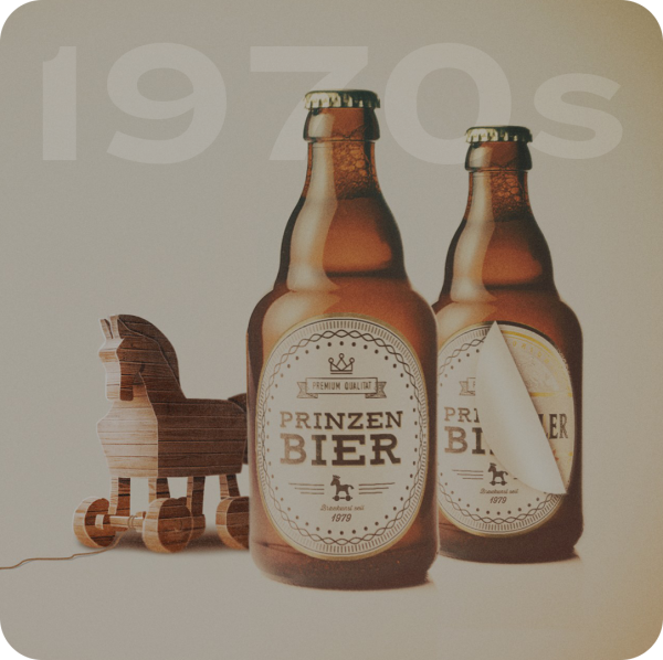 Two brown beer bottles with vintage labels stand next to a wooden toy horse.